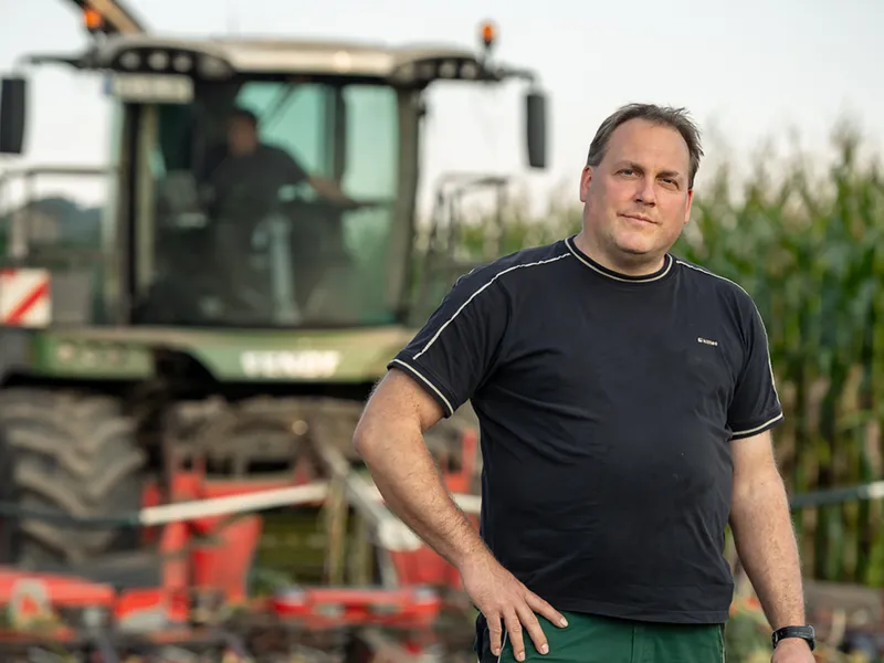 engagierter Landwirt mit Traktor im Hintergrund
