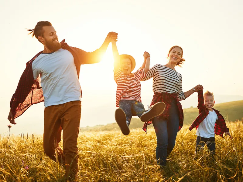 fröhliche Familien streift bei Sonnenschein über ein herbstgelbes Feld