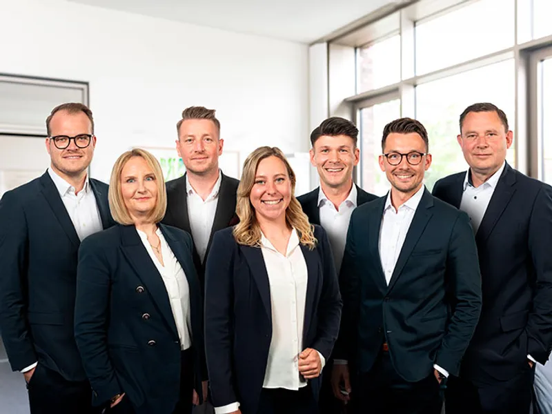 Das Bild zeigt das Team der Bezirksdirektion Hannover vor dem Gebäude mit Mini in der Mitte