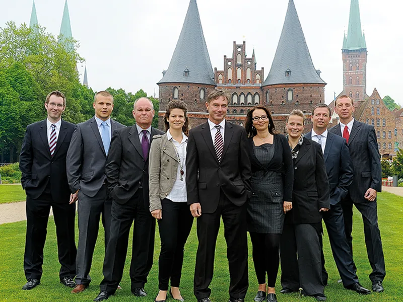 Das Team der Bezirksdirektion Lübeck posiert vor der historischen Skyline der Stadt