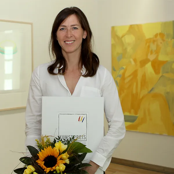 Katharina Neuweg mit Urkunde und Blumenstrauss vor ihren Werken