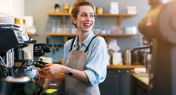 Barista beim Michaufschäumen ist total dem Kunden zugewandt