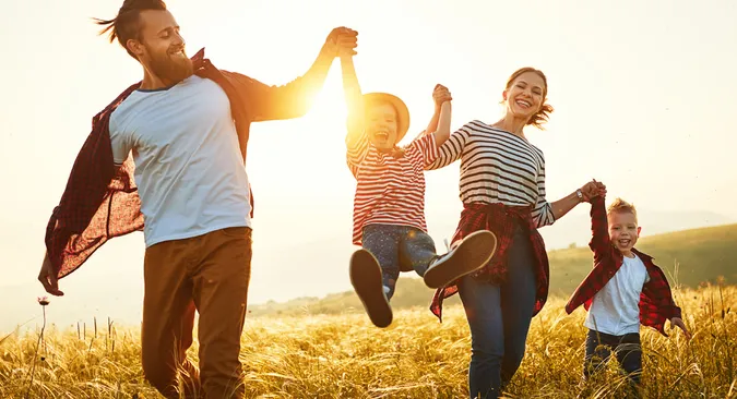 fröhliche Familien streift bei Sonnenschein über ein herbstgelbes Feld